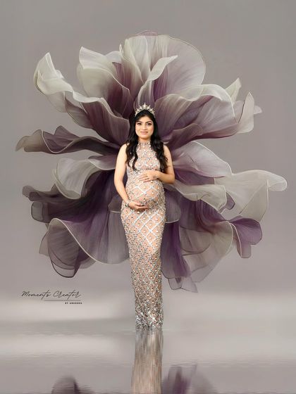 An artistic and ethereal portrait. The giant floral prop behind the mom-to-be creates a wing-like effect, transforming her into a magical, blooming figure.