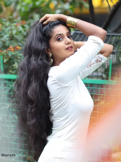 A candid shot of the model in the white dress, with a natural pose and expression. The lighting is soft and flattering.