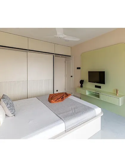Another angle of the master bedroom, highlighting the seamless integration of the wardrobe and TV unit. The light color palette makes the room feel spacious and tranquil.