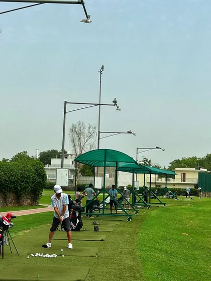 A golfer sets up for a shot on the mat, with our portable canopies providing shade on a sunny day.