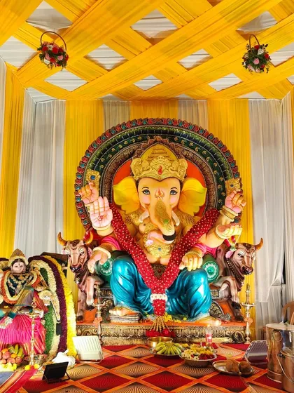 A close-up of the main stage for the Ganesh Chaturthi celebration. We used bright yellow and white striped fabric for the backdrop and ceiling, ensuring the focus remains on the beautifully adorned Ganesha idol.