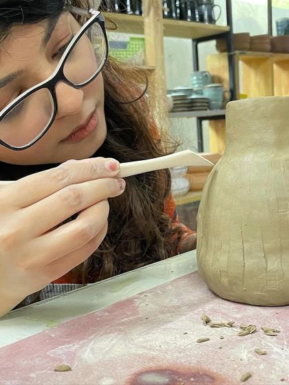 Using a wooden tool to add texture to a hand-built vase. This carving technique creates beautiful shadows and depth on the final piece.