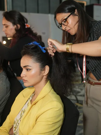 A student creates a sleek, high ponytail backstage, a classic runway hairstyle that requires skill and precision. Our hair artistry training is as comprehensive as our makeup courses.