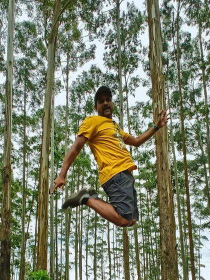 A traveler caught mid-jump in the pine forests of Kodaikanal. It's about feeling free and alive in nature.