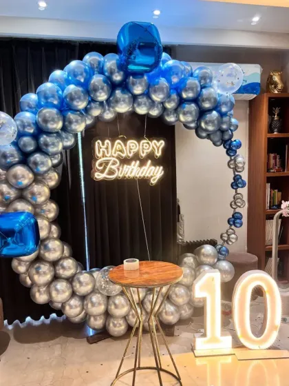 A 10th birthday party with a blue and silver chrome balloon ring, a neon sign, and a "10" marquee number.
