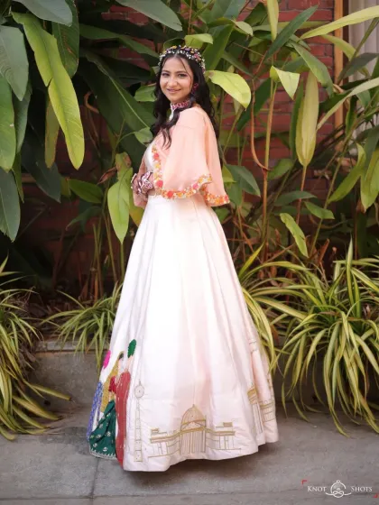 A full view of the unique, hand-painted lehenga. The soft, natural makeup and wavy hair let the outfit be the star.