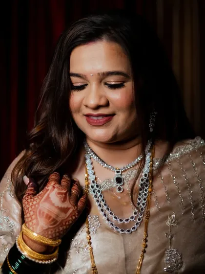 A close-up of the bride, focusing on her intricate henna and beautiful jewelry. Her gentle smile and downcast eyes capture a moment of quiet happiness during her wedding ceremony.