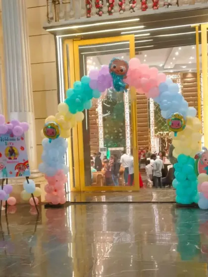A Cocomelon-themed entrance arch in pastel colors welcomes guests to a fun-filled first birthday party.