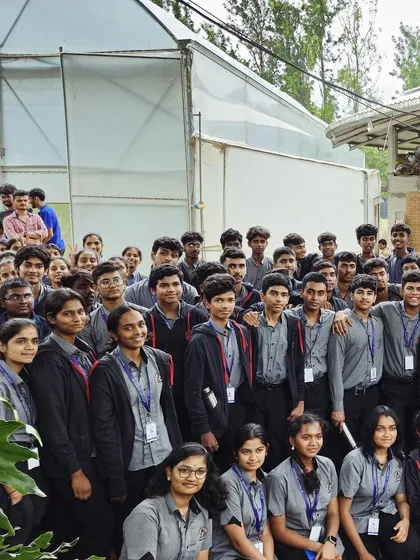 A group photo of the bright students from Trinity College, Mysore, with our greenhouse in the background. We aim to inspire future leaders to think critically about our food systems.