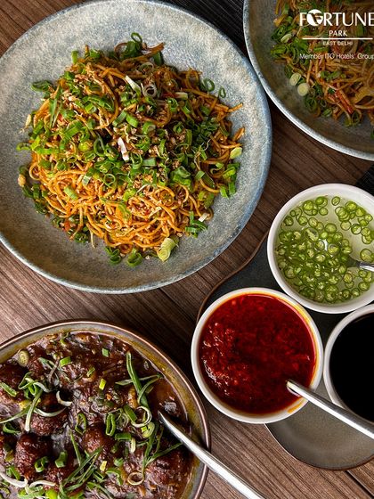 A spread of our popular Indo-Chinese dishes, including flavorful noodles and Manchurian, served with an assortment of sauces.