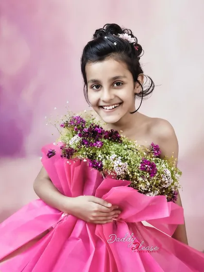 A happy, close up shot of the girl in the flower dress, showing her bright smile. This captures the fun and joy of a creative photoshoot.