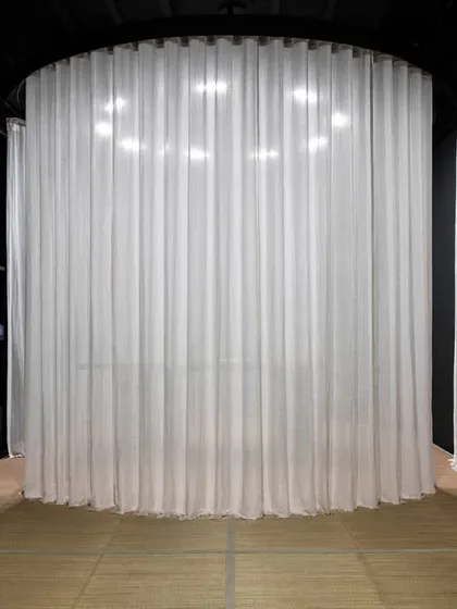 The cylindrical display pod is shown here fully shrouded by sheer white curtains. This 'veiled' state conceals the product, building anticipation and transforming the act of shopping into a moment of gradual, controlled revelation.