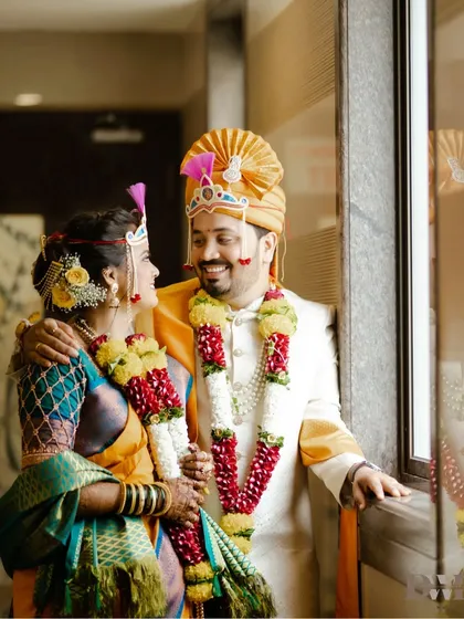 A beautiful portrait of the newly married couple by a window, sharing a happy and relaxed moment.