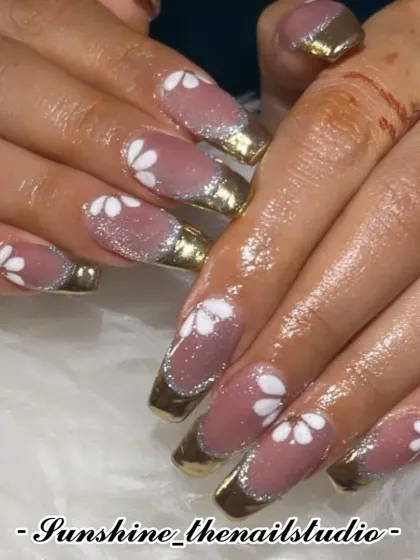 A gold chrome French manicure with hand-painted white flowers.