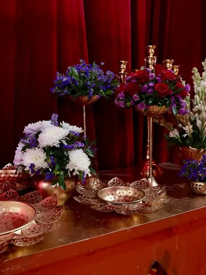 A close-up of the console decor, featuring a mix of purple and white flowers in ornate brass bowls and vases, perfectly matching the royal aesthetic.