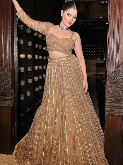 A full-length shot showcasing the unique silhouette of the golden lehenga. The styling is perfect for a cocktail party or reception.