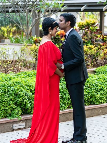 A tender moment between a couple, with the mom-to-be in a flowing red A-line gown. The cape adds a touch of elegance and movement to this classic walking shot.