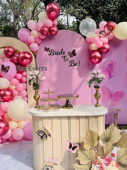 A full view of the lovely butterfly-themed bridal shower decor. The setup includes arched backdrops, a large balloon garland, and a dessert table, all adorned with delicate butterflies.