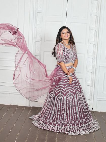 The sheer dupatta with its embellished border adds a layer of grace without hiding the detailed work on the blouse. This rental lehenga is designed for both style and comfort.
