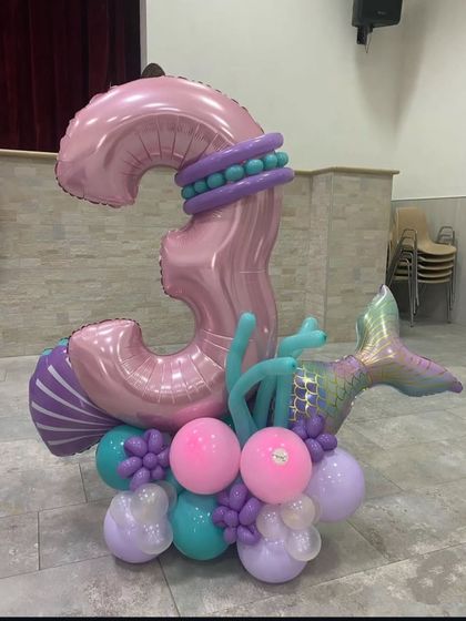 A unique mermaid-themed balloon sculpture of the number "3". The design incorporates a mermaid tail and shell details, making it a standout piece for the party.