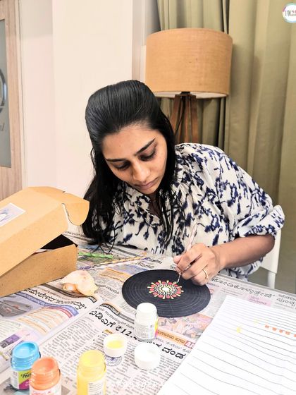 A participant is deeply focused on creating a dot mandala, carefully placing each dot to build a complex and beautiful pattern.