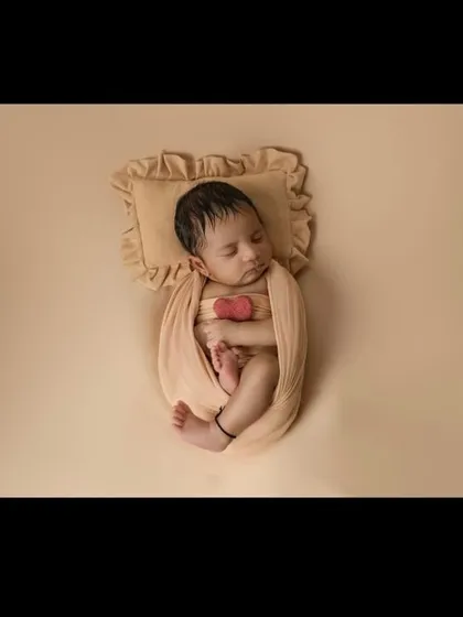 A top-down view of a swaddled newborn, showing their tiny feet peeking out. This pose is a favorite for showcasing their delicate proportions and curled-up comfort.
