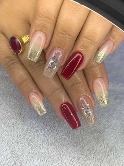 A beautiful combination of deep red, gold glitter, and translucent nails with embedded silver butterfly charms.