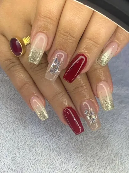 A classic holiday combination of deep red and gold glitter on long, coffin-shaped nails, with silver butterfly accents.