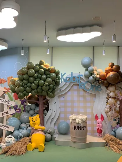 Another angle of the Hundred Acre Wood backdrop, showing the gingham-print panel and the adorable Piglet figure next to a "Hunny" barrel.