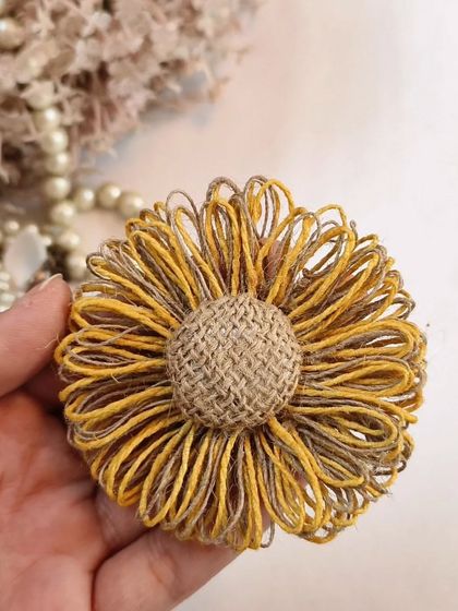 A close-up of the handcrafted jute flower statement earring, showing the detail of the woven material.