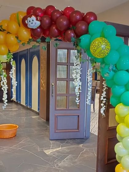 A colorful balloon arch at the entrance of the jungle party venue.