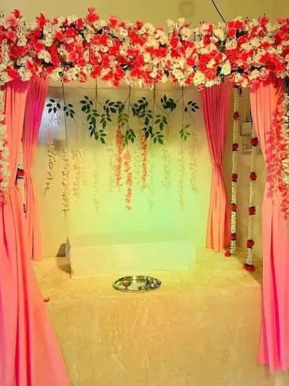 Another view of the pink draped canopy with red and white flowers. This angle shows how the structure fits perfectly within a home space, transforming a corner into a sacred spot for worship.