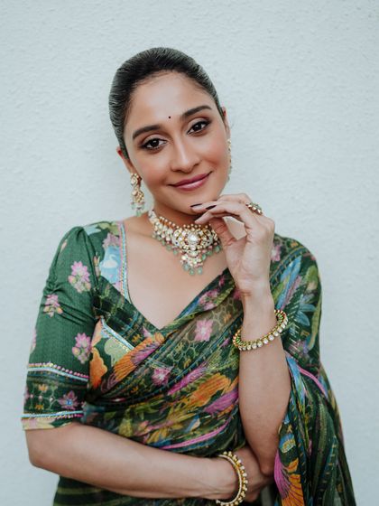 This portrait captures the model's direct and engaging gaze. The simple background ensures all attention is on her and the beautiful floral saree.