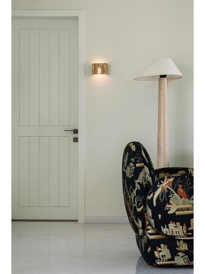 A detail of the family lounge, showing a statement armchair with a whimsical pattern next to a simple, elegant door.