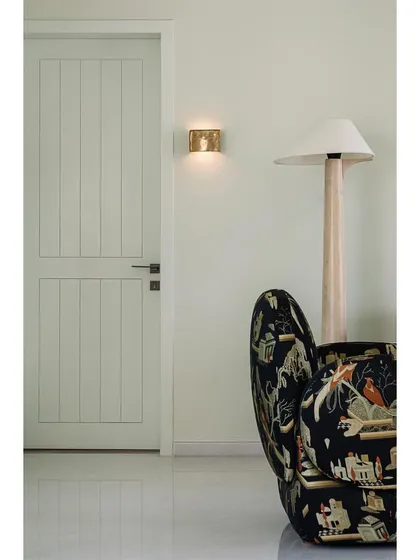 A detail shot from the family lounge, showing a patterned armchair and a minimalist floor lamp. It's a space designed for laid-back family time.