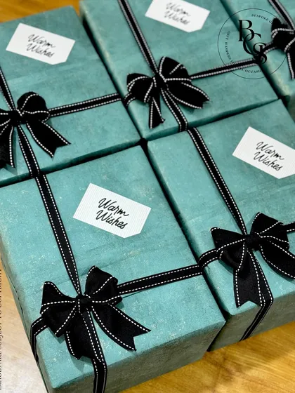 A close-up of our sophisticated teal and black gift wrapping. The high-quality textured paper and stitched grosgrain ribbon create a premium feel, suitable for discerning corporate clients or personal gifting.
