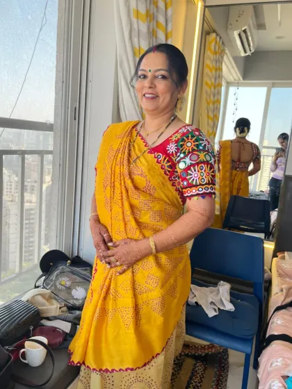 A full-length view of the groom's mom in her vibrant yellow saree. She looks absolutely beautiful and ready for the wedding rituals.