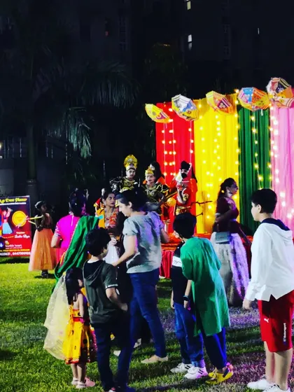 A stage setup for a performance during a society's dandiya night. The backdrop is colorful and lit with fairy lights, creating a focal point for the event's cultural activities.