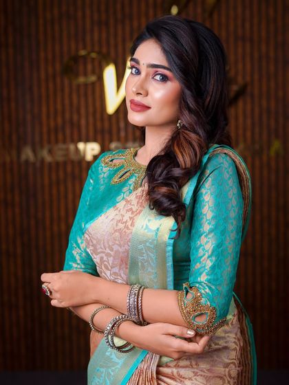 This model is wearing a unique beige and teal saree. The drape is styled to highlight the unusual color combination and the intricate blouse neckline.