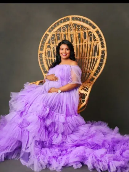 Seated like a queen in a peacock chair, this mom-to-be looks radiant in our lavender off-the-shoulder tulle gown.