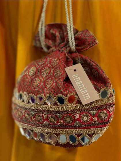 A close-up of the red mirror-work potli, showing the intricate details and the vibrant colors of the embroidery.