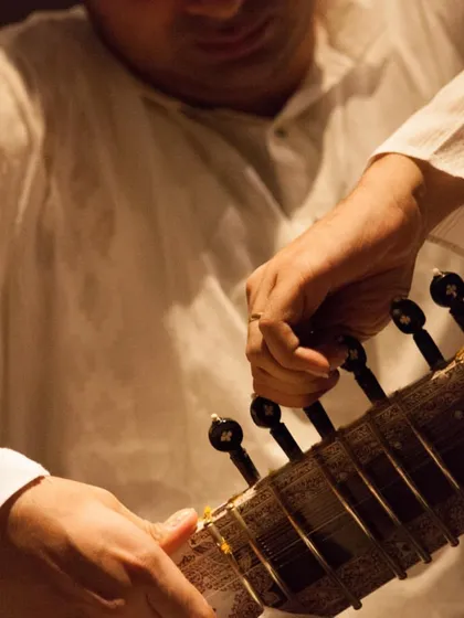A close-up of the tuning process. Tuning a sitar is an art in itself, involving the main playing strings, the chikari drone strings, and the sympathetic strings that resonate underneath.