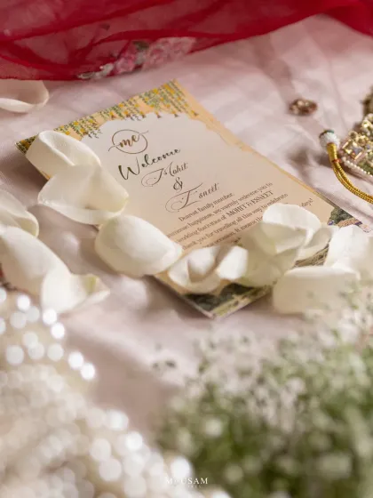 A beautiful flatlay of the wedding invitation, surrounded by rose petals and pearls. This shot captures the first chapter of the couple's story and the elegant details of their day.