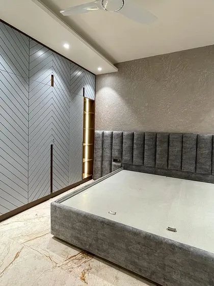 We believe a bedroom should be a reflection of personal style. For this modern bedroom, we used a sophisticated grey palette. The chevron pattern on the wardrobe doors adds a trendy, graphic element, while the upholstered bed and rustic concrete-texture wall create a calm, inviting atmosphere.