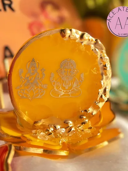 A close-up of the yellow Lakshmi Ganesh standee. The geode-style edge and gold detailing highlight the intricate engraving of the deities, creating a truly divine piece.