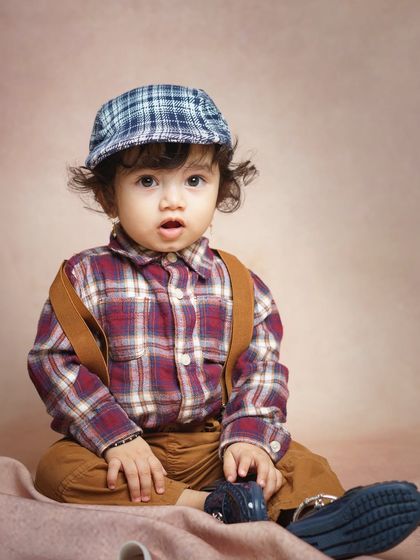 A curious and expressive portrait of a baby boy in our studio. The combination of a vintage-style cap and a classic outfit gives this photo a timeless, storybook feel.