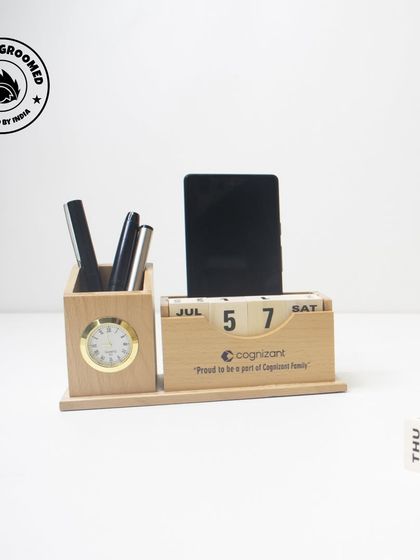 This wooden desk organizer is a timeless and functional gift. It features a perpetual calendar, a pen stand, a mobile holder, and a clock, all customized for our client, Cognizant.