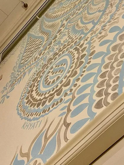 A close-up showing my signature on the Delhi mural. The fine lines and delicate patterns in silver and aqua blue create a look that is both intricate and understated.