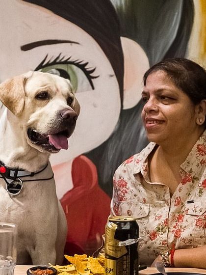 A candid moment between a guest and a beautiful Labrador against our signature anime and dog mural.