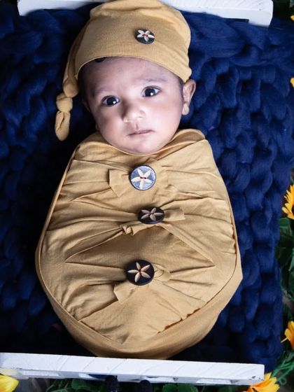 Sweet as can bee. This themed newborn photo features adorable bumblebee props and sunflowers, creating a bright and cheerful portrait for this little baby.
